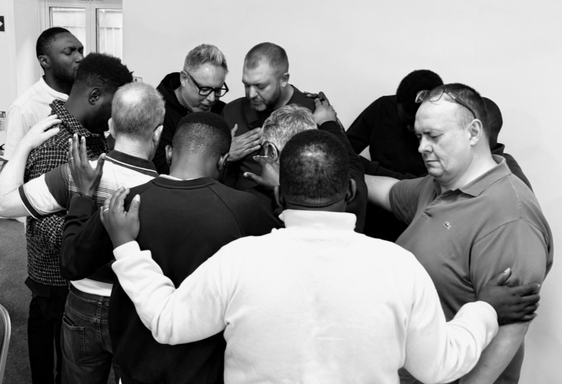 Black and white image of men praying at the MPower event