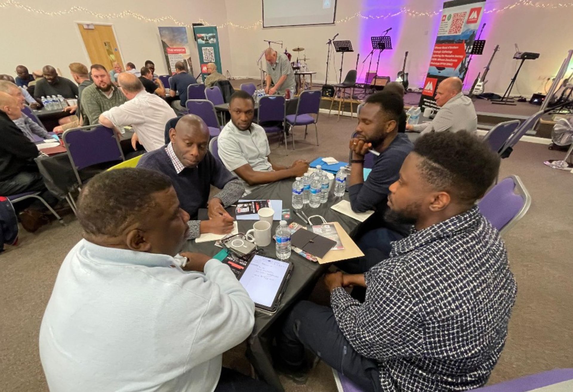 Photograph of groups of men seated at tables during the MPower event