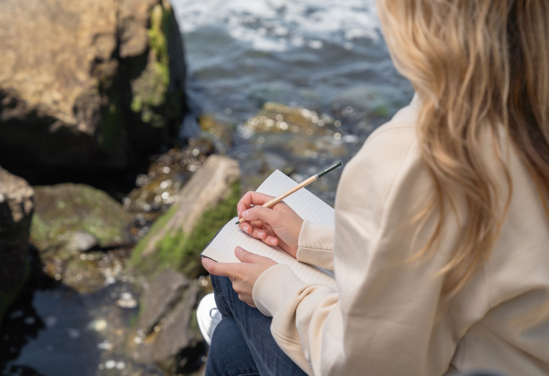 Photograph of a woman by the sea journalling