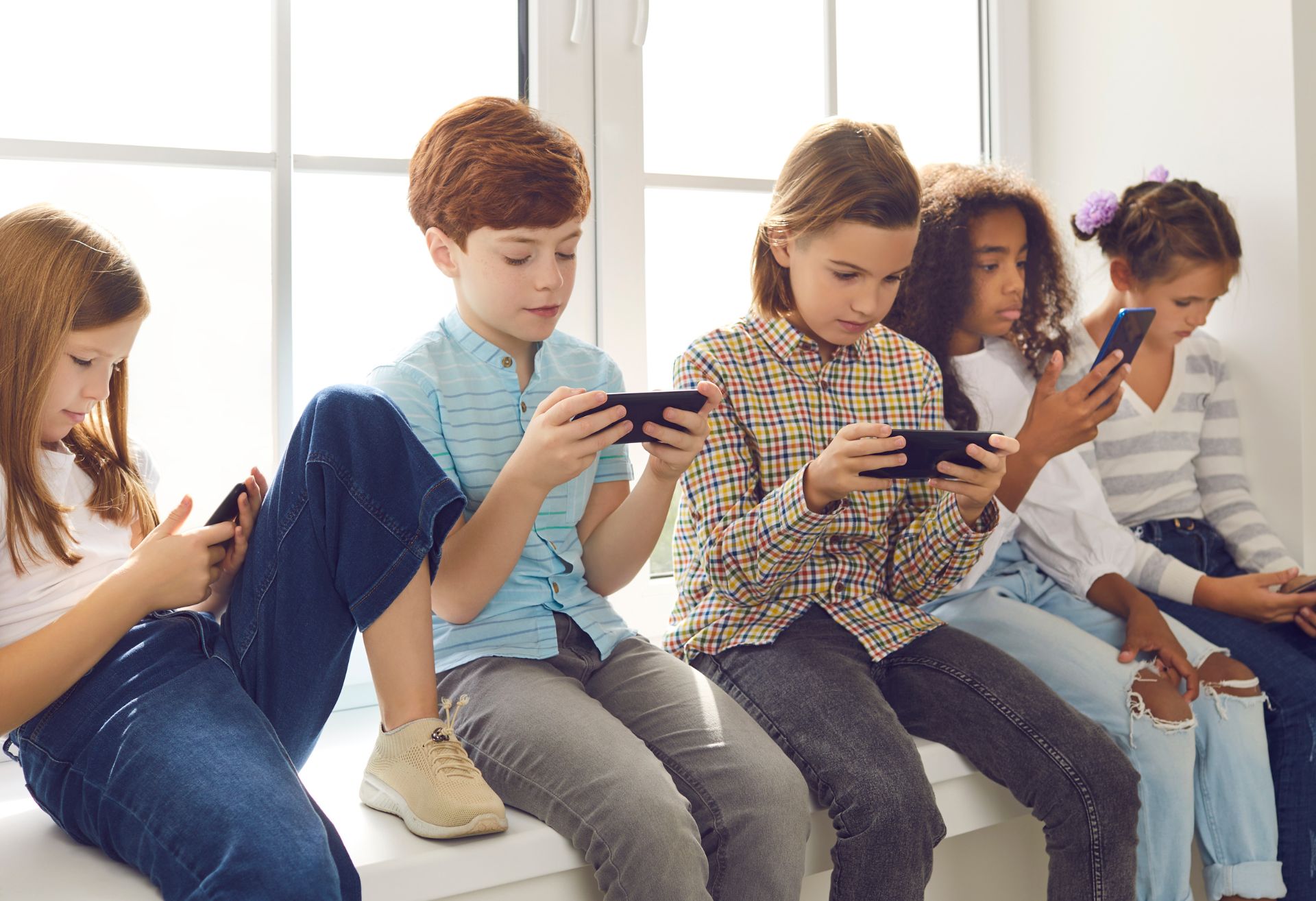 Picture of children sitting on a bench all on their phones